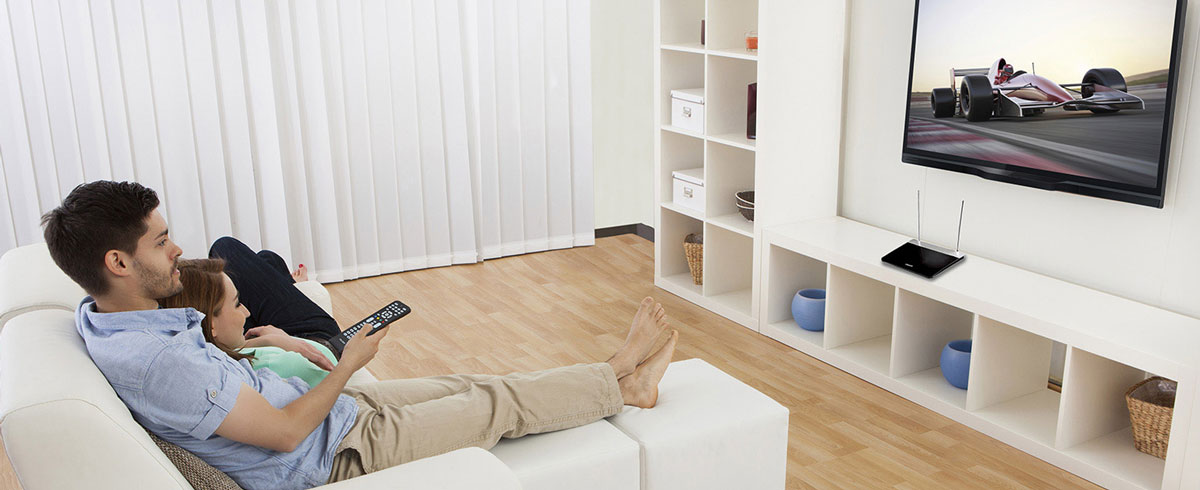 Un uomo e una donna seduti su un divano, che guardano la televisione