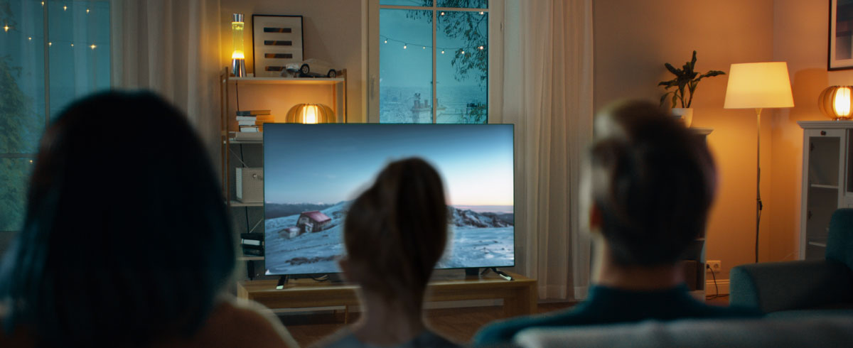 Famiglia riunita in un soggiorno impegnata a guardare un televisore a grande schermo