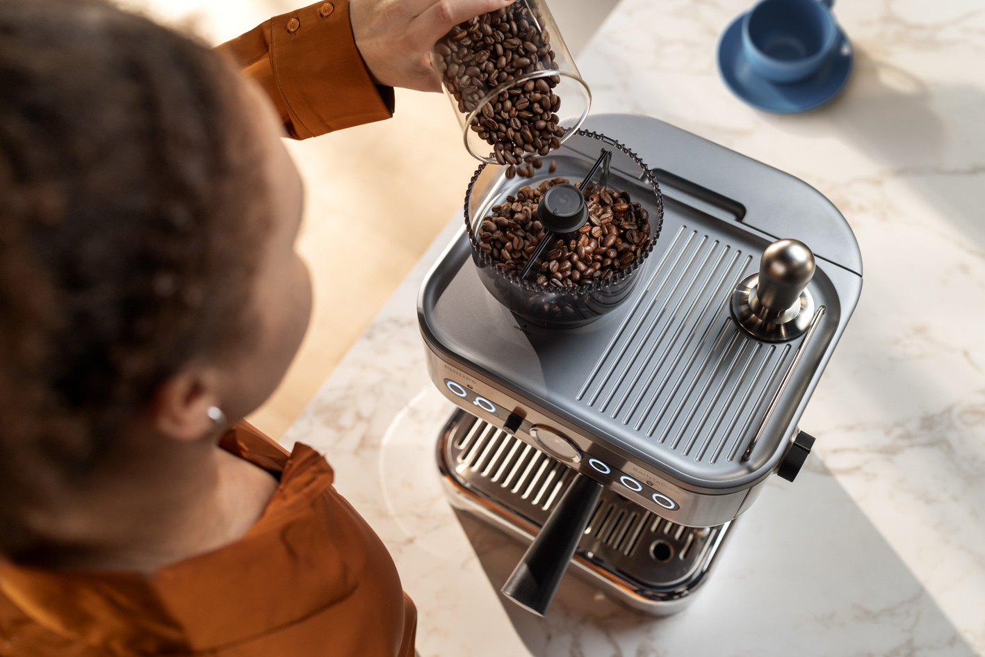 Una giovane donna che versa il caff&egrave; in grani nell'apposito recipiente di Philips Barista Brew