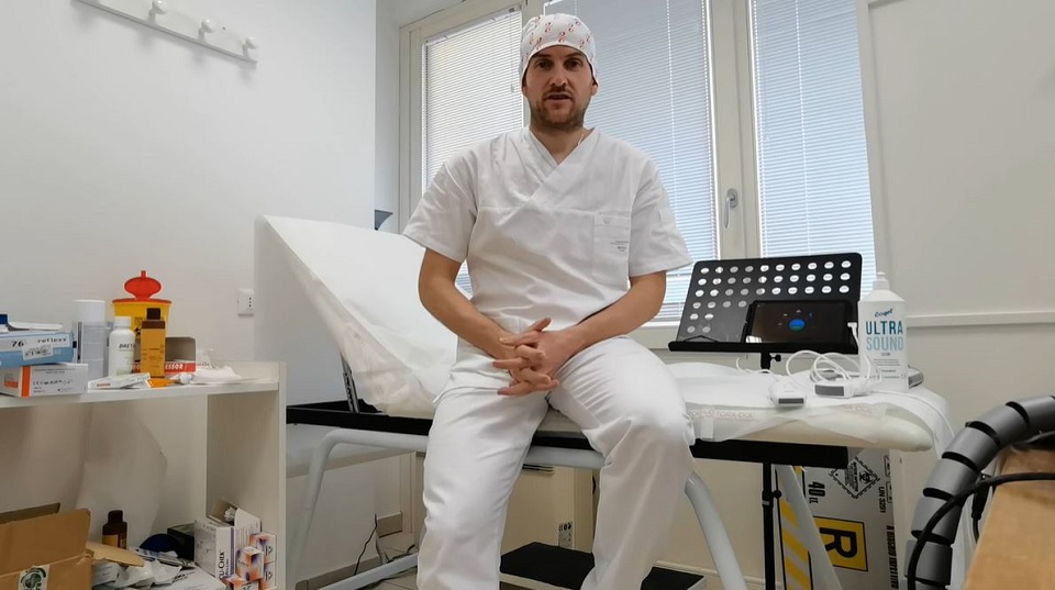 un uomo in camice bianco e berretto seduto su un tavolo